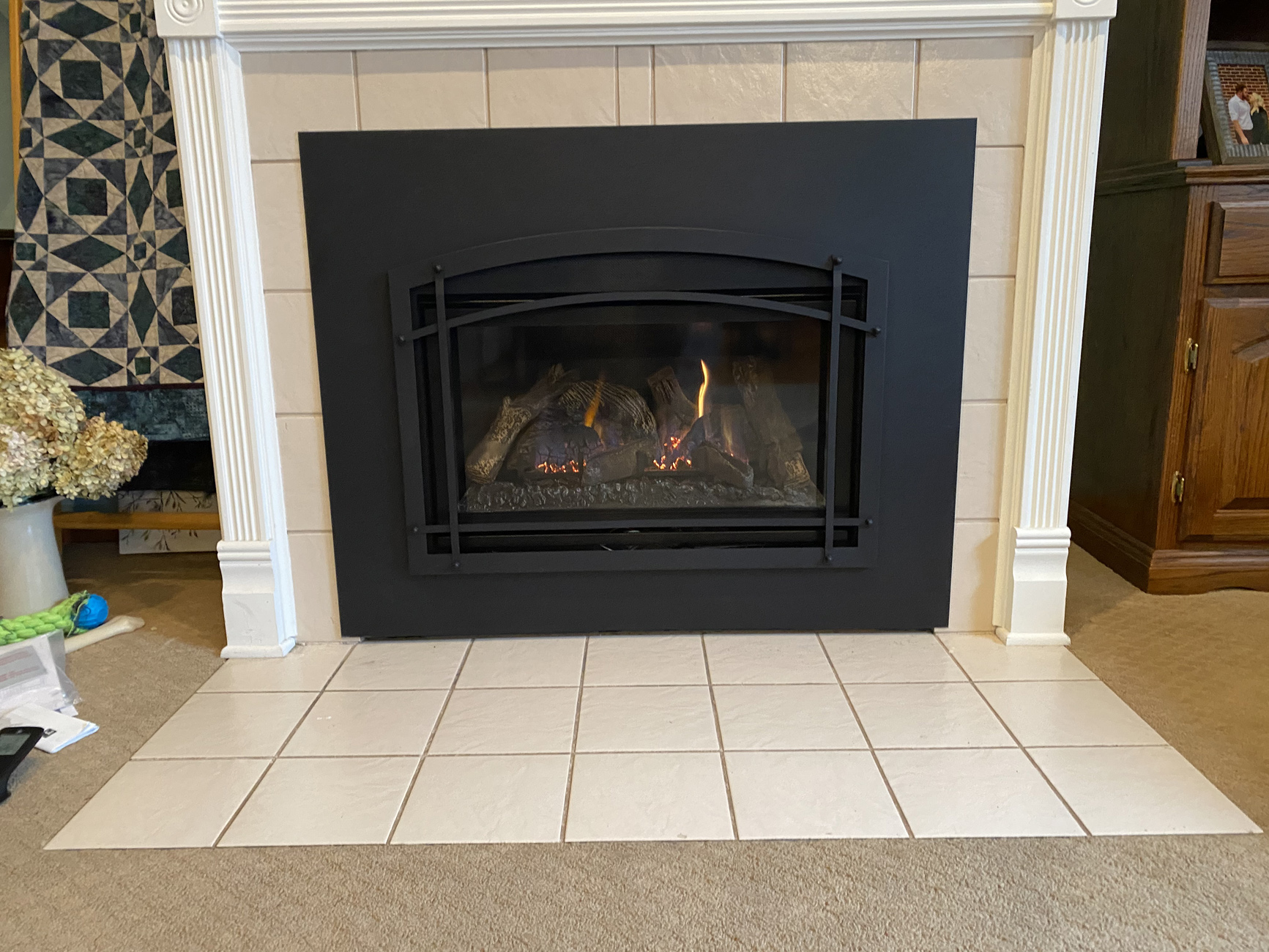 Warm fireplace framed by a cream tile surround